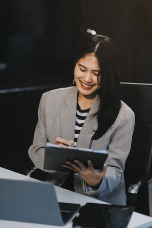 Young Asian businesswoman is happy to work at the modern office using a tablet.の写真素材