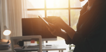 Smiling businesswoman using her phone in the office. Small business entrepreneur looking at her...