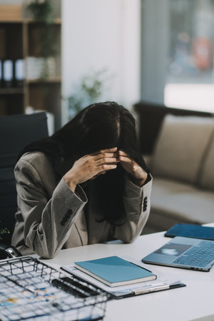 Young Asian woman feeling migraine head strain. Tired, Overworked businesswoman financier while...