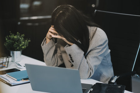 Young Asian woman feeling migraine head strain. Tired, Overworked businesswoman financier while...