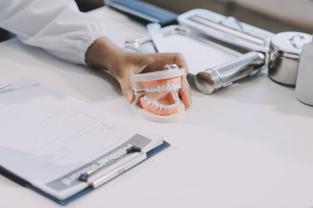 A dentist is using specialized dental equipment to inspect dentures to study the anatomy of the teeth before using the knowledge to treat patients, Dentures are being studied by oral specialists.の写真素材
