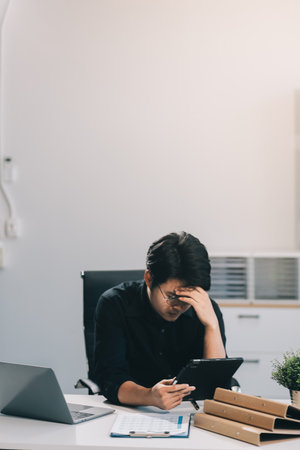 Frustrated Asian young businessman worker working on table in office. Busy employee worker people...