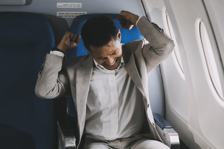 Stressed and professional Asian businessman in a business class, having a serious phone call with someone during the flight to a business meeting.の写真素材