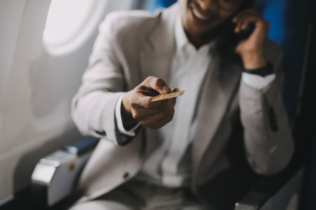 Businessman holding credit card and looking at camera near laptop in private jetの写真素材