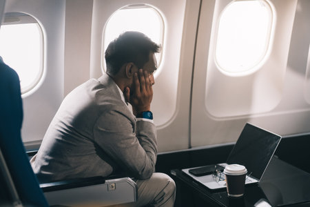 Stressed and professional Asian businessman in a business class, having a serious phone call with...