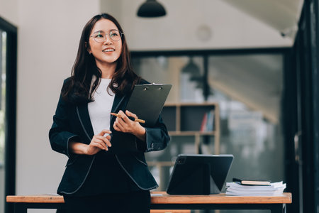 Happy young asian woman, using digital tablet isolated on office backgroundの写真素材
