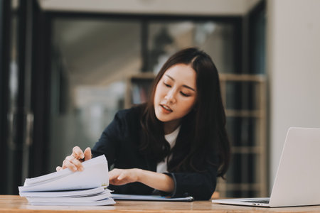 Cheerful business lady working on laptop in office, Asian happy beautiful businesswoman in formal suit work in workplace. Attractive female employee office worker smile.の写真素材
