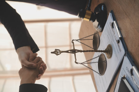 Lawyer shaking hands with a client making about documents, contracts, agreements, cooperation agreements with a female client at the lawyer's desk and a hammer at the table.の写真素材