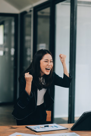 Asian business woman are delighted and happy with the work they do on their tablet, laptop and taking notes at the modern office.の写真素材