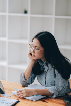 Portrait of Asian young female working on laptop and financial report at office.の写真素材