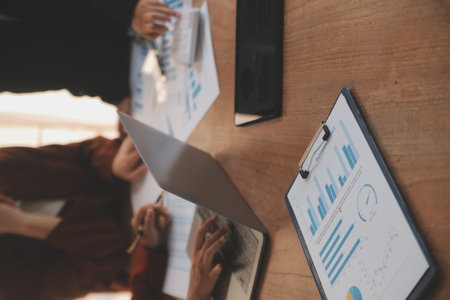 Group of confident business people point to graphs and charts to analyze market data, balance sheet, account, net profit to plan new sales strategies to increase production capacity.の写真素材