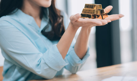 Portrait of a beautiful young businesswoman holding gold bar at office deskの写真素材