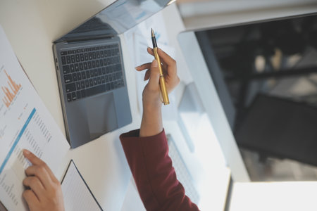 Cropped image of professional businesswoman working at her office via laptop, young female manager using portable computer device while sitting at modern loft, flare light, work process conceptの写真素材