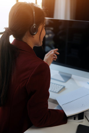 Friendly female helpline operator in call center. Young woman working in call center and holding microphone on headset with hand.の写真素材