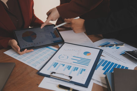 Group of confident business people point to graphs and charts to analyze market data, balance sheet, account, net profit to plan new sales strategies to increase production capacity.の写真素材