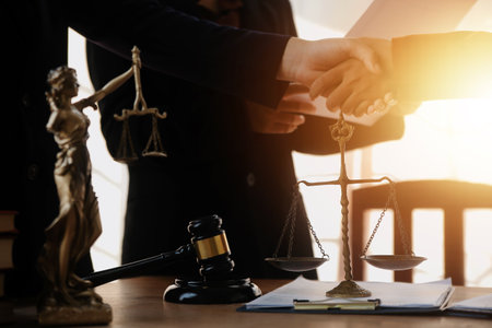 Lawyer shaking hands with a client making about documents, contracts, agreements, cooperation agreements with a female client at the lawyer's desk and a hammer at the table.の写真素材