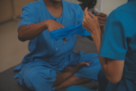 Professional physical therapist examines and cares for a young man in a physical therapy center,...