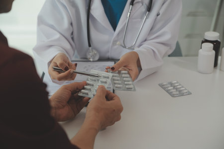 Doctor prescribing medicine giving pills to senior grandmother patient at hospital.の写真素材