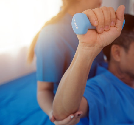 Physiotherapist man giving exercise with dumbbell treatment About Arm and Shoulder of athlete male patient Physical therapy conceptの写真素材