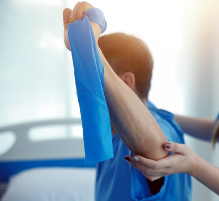 Close up hand patient doing stretching exercise with a flexible exercise band and a physical therapist hand to help in clinic room.の写真素材