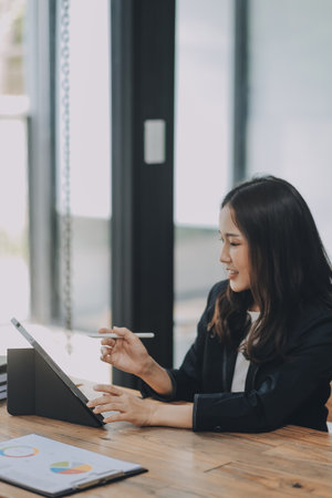 Pretty young Asian businesswoman working on laptop and taking notes In office.の写真素材
