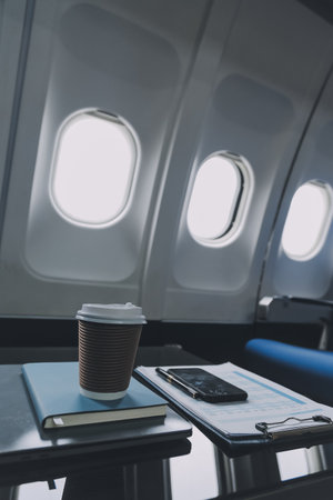 Cup of coffee with laptop and notebooks on table in airplaneの写真素材