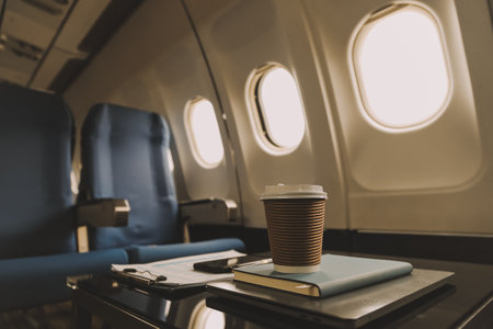 Cup of coffee with laptop and notebooks on table in airplaneの写真素材