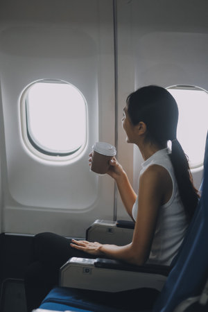Businesswoman smiling while sitting in airplane seat. Concept of business travel and professional journeyの写真素材