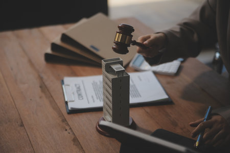 Real Estate Law, Home Insurance, property Tax, Auction and Bidding concepts. small toy house model with gavel justice hammer on desk in courthouse.の写真素材