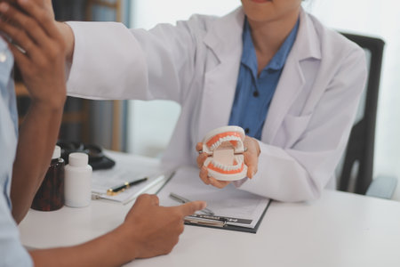 Dentist consultation - patient visit at the dental clinic office. Female dentist wearing dentures to...