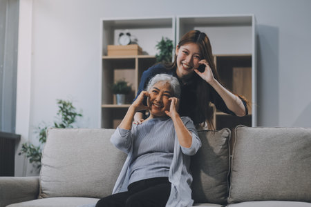 Adult daughter old mom hugging sit on couch enjoy pleasant positive talk, remembering funny occasion from life spend weekend together, caring about older generation relatives express attention conceptの写真素材