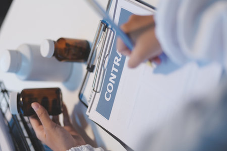 Doctor sitting at desk and writing a prescription for her patientの写真素材
