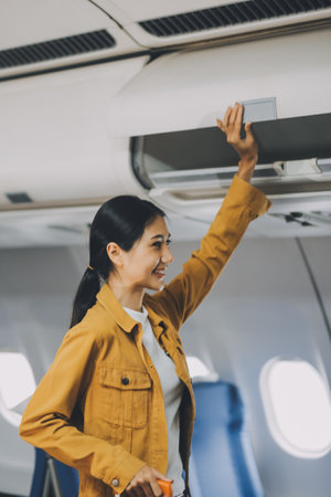 Young Female Tourist with Luggage Walking Through Airplane Cabin Ready for Travel Adventureの写真素材