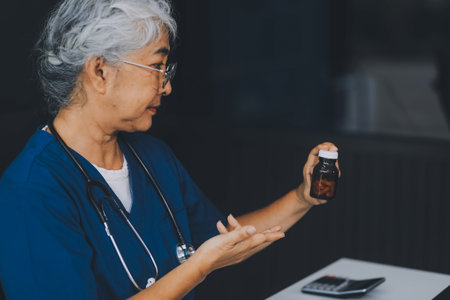 A woman doctor is writing on a clipboard and holding a bottle of pills. She is smiling and seems to be in a good moodの写真素材