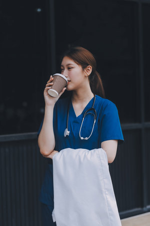 Confident nurse on her way to work in a clinic. Pretty female nurse drinking coffee and rest after...