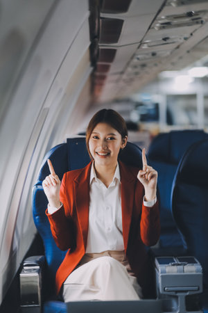 A young Asian woman, seated as an airplane passenger, contemplates dollar bills, reflecting on lucrative opportunities and aspirations towards billionaire status.の写真素材