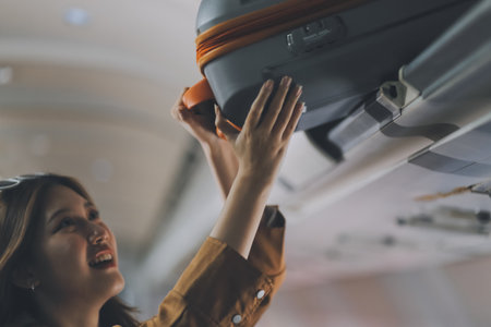 Female tourist packing her luggage in the airplane cabin.の写真素材