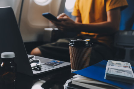 Attractive Asian businesswoman traveling on airplane playing with mobile phone while sitting in cabin.の写真素材
