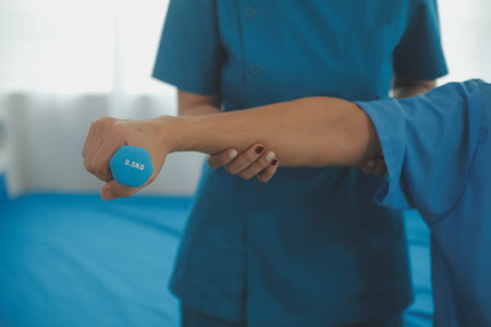 Physiotherapist man giving exercise with dumbbell treatment About Arm and Shoulder of athlete male patient Physical therapy conceptの写真素材