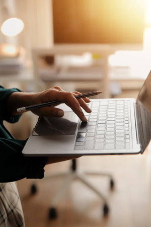 Female Manager Using Laptop Computer To Check Inventory. In the Background Warehouse Retail Center with Cardboard boxes, e-Commerce Online Orders, Food, Medicine, Products Supply. Over the Shoulderの写真素材