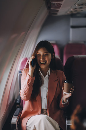Attractive Asian female passenger of airplane sitting in comfortable seat while working laptop and tablet with mock up area using wireless connection. Travel in style, work with grace.の写真素材