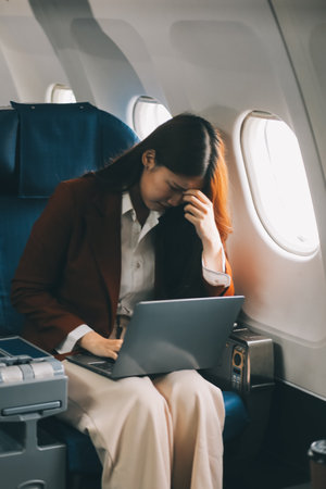 Photo of a frustrated woman sitting on an airplane with her head in her hands. Asian woman sitting in a seat in airplaneの写真素材
