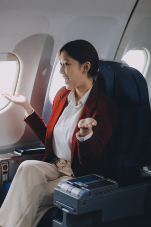 A young Asian woman, seated as an airplane passenger, contemplates dollar bills, reflecting on lucrative opportunities and aspirations towards billionaire status.の写真素材