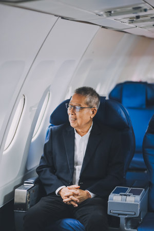 Attractive Asian male passenger of airplane sitting in comfortable seat while working laptop and tablet with mock up area using wireless connection. Travel in style, work with grace.の写真素材
