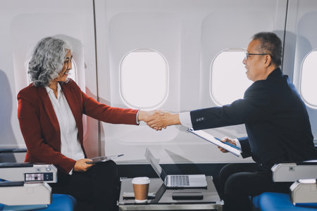 business people at meeting in private plane, Asian businessman in suit is talking to woman in jet...