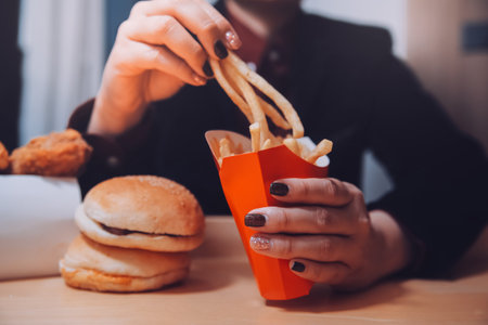 Asian woman holding french fries and eating happily in restaurantの写真素材