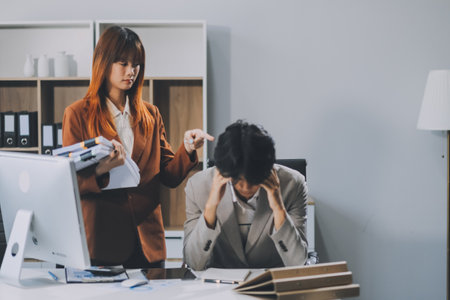Stressed business couple working at big cabinet. Frustrated director closed face with hands at laptop workplace interior. Woman partner solving problems on smartphone call feeling nervous at officeの写真素材