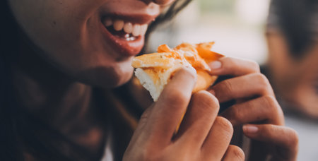 Funny brunette girl in yellow sweater eating pizza at restaurant.の写真素材