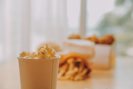 A bucket of popcorn, top-view, warm colors, light brown wooden background, flat lay, daylight macro close-upの写真素材