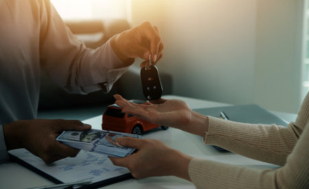 Young man receives a key from car salesman. After agreeing to a contract for rent or sale of a car at workshop, loan car, insurance, sale, buying car and finance concept.の写真素材
